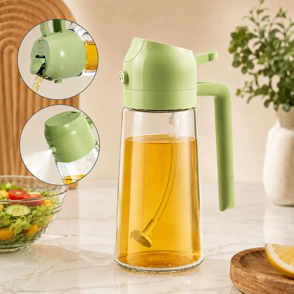 A light green and clear glass oil dispenser pitcher filled with golden oil, shown on a kitchen counter with two circular inset close-ups of the spout and pour mechanism. A salad bowl, lemon slice, and vase of greenery are softly blurred in the background.