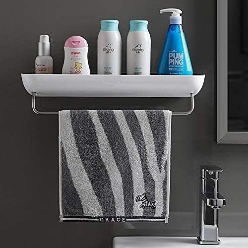 A wall-mounted bathroom shelf with a white tray and chrome bar holding four toiletry bottles and a blue pump bottle, with a gray-and-white striped towel hanging below. The towel reads GRACE.