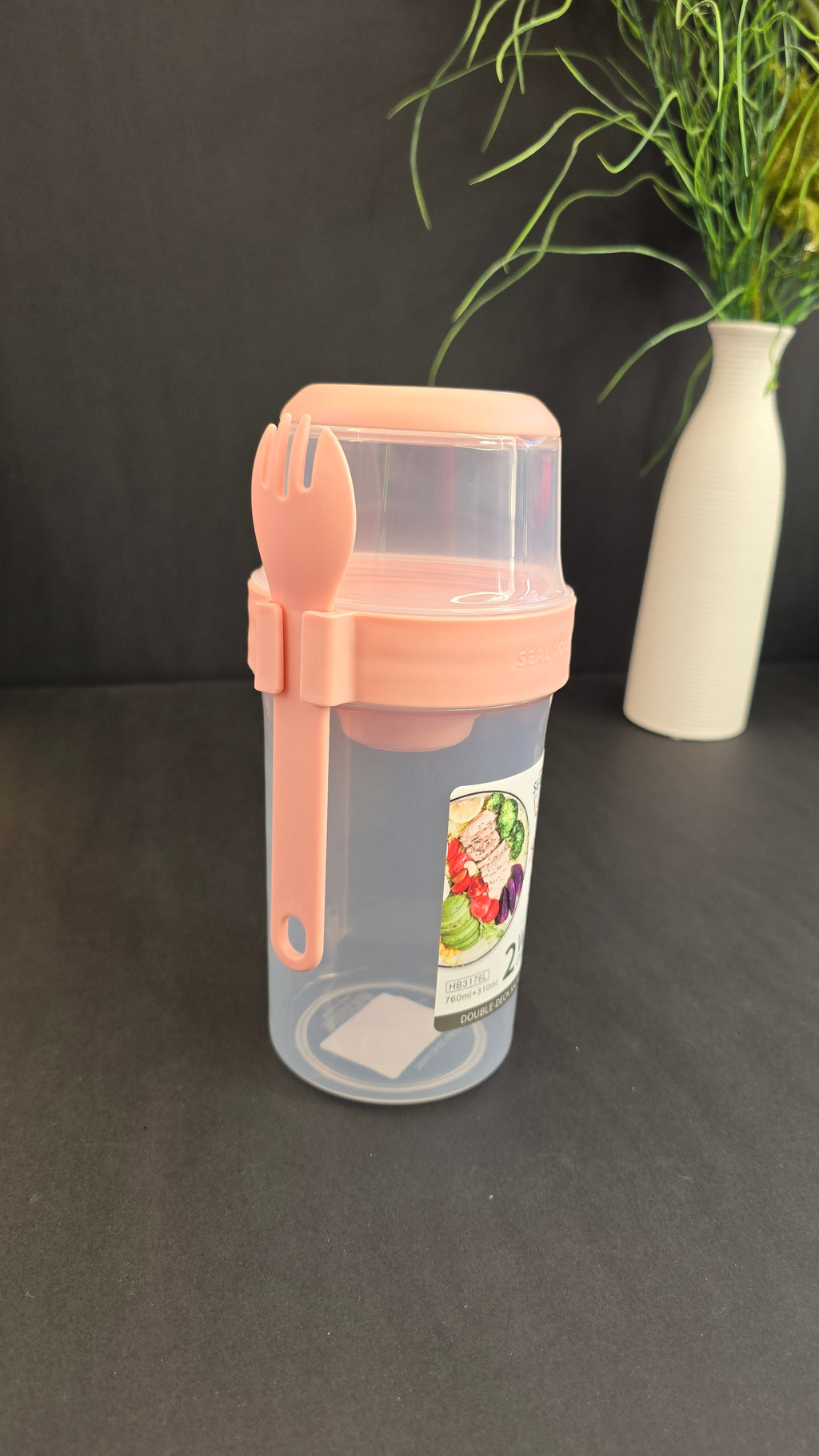 Pink double-deck salad container with clear compartments and attached reusable fork