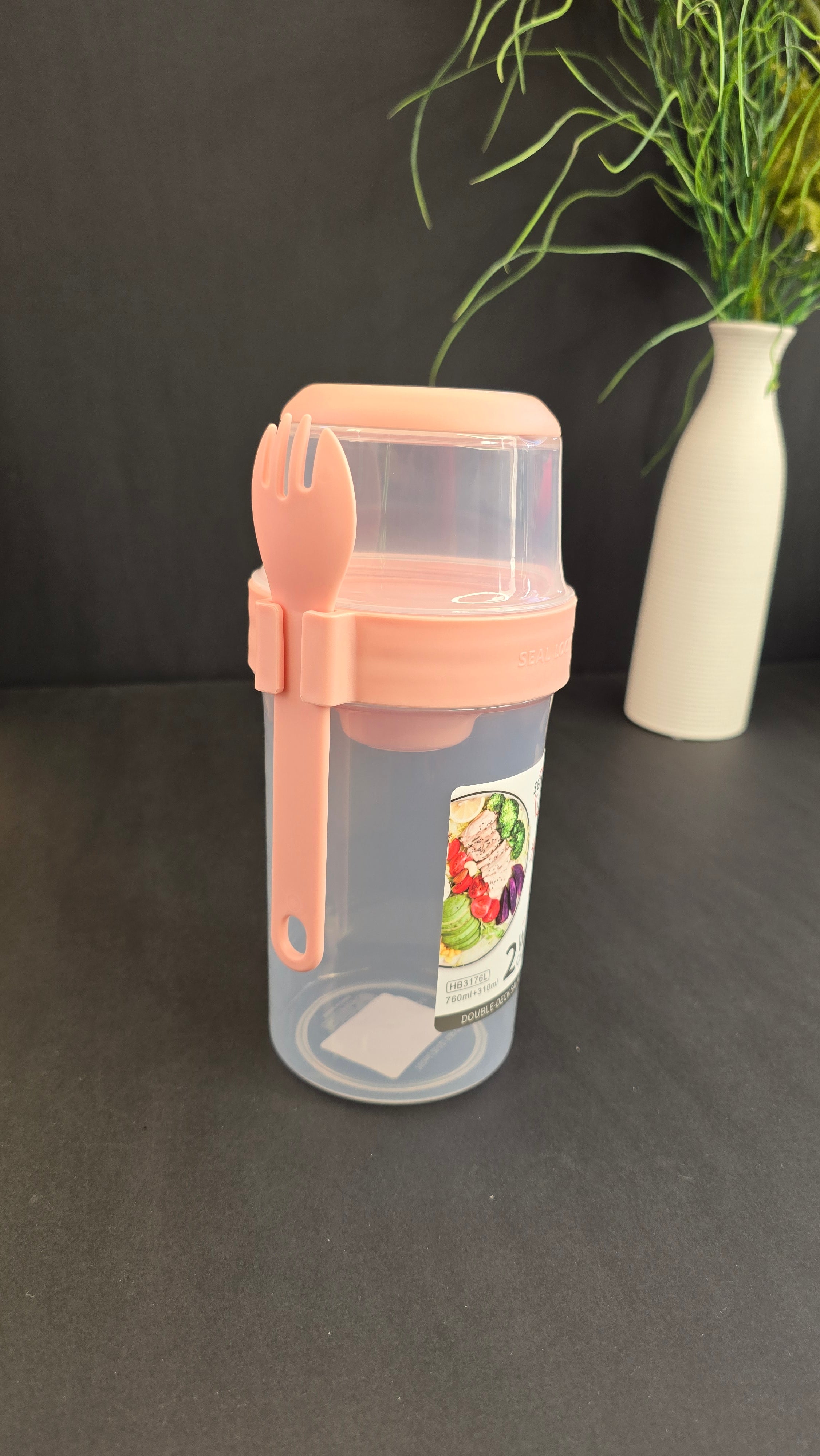 Pink double-deck salad container with clear compartments and attached reusable fork