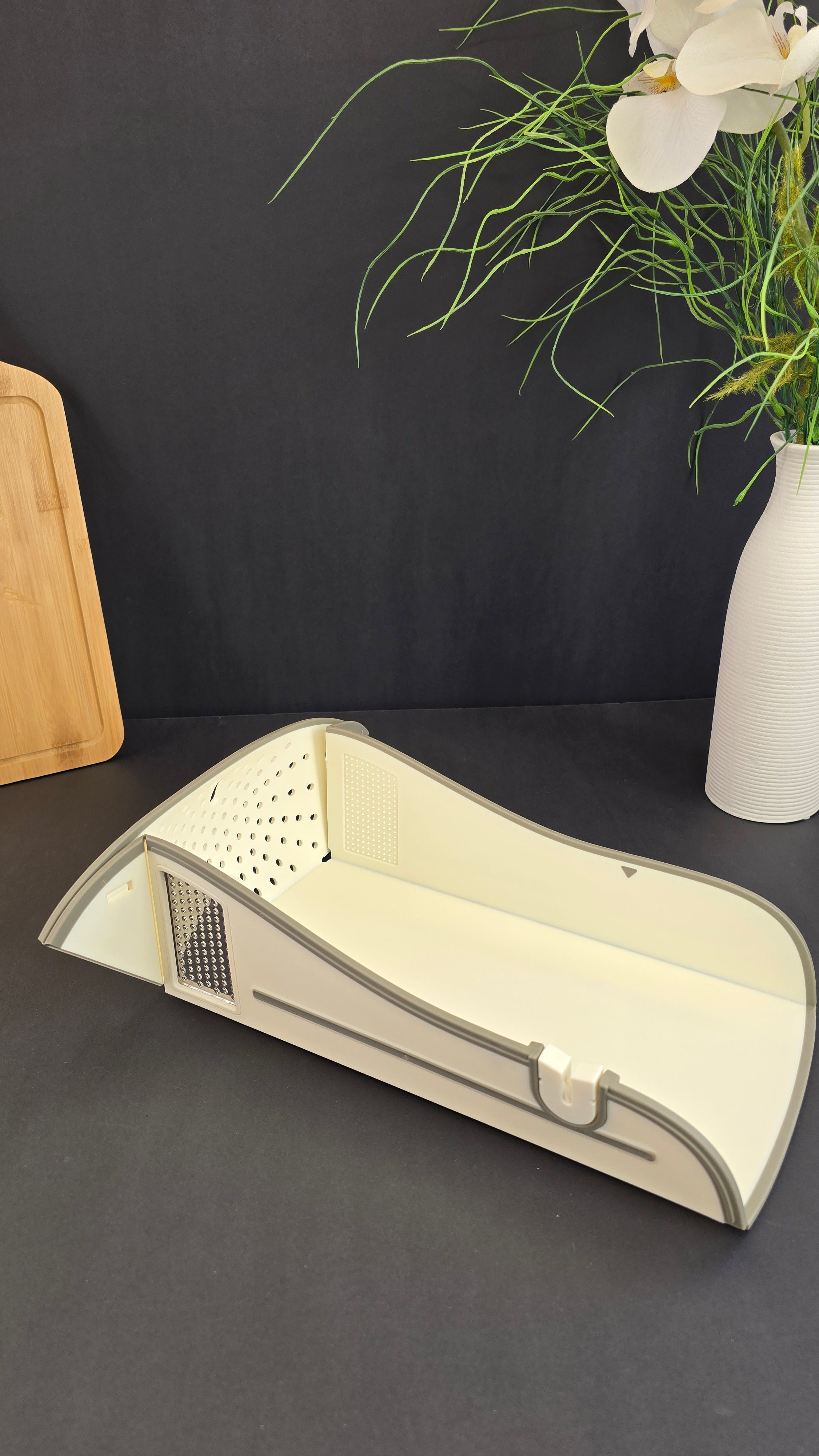 Angled view of the multifunctional foldable cutting board with integrated stainless-steel grater