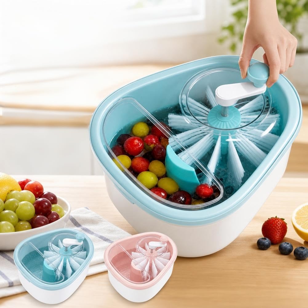 A countertop fruit washing and draining basket shown in use, with a hand turning the lid. The main unit is white and light blue, filled with mixed fruit.