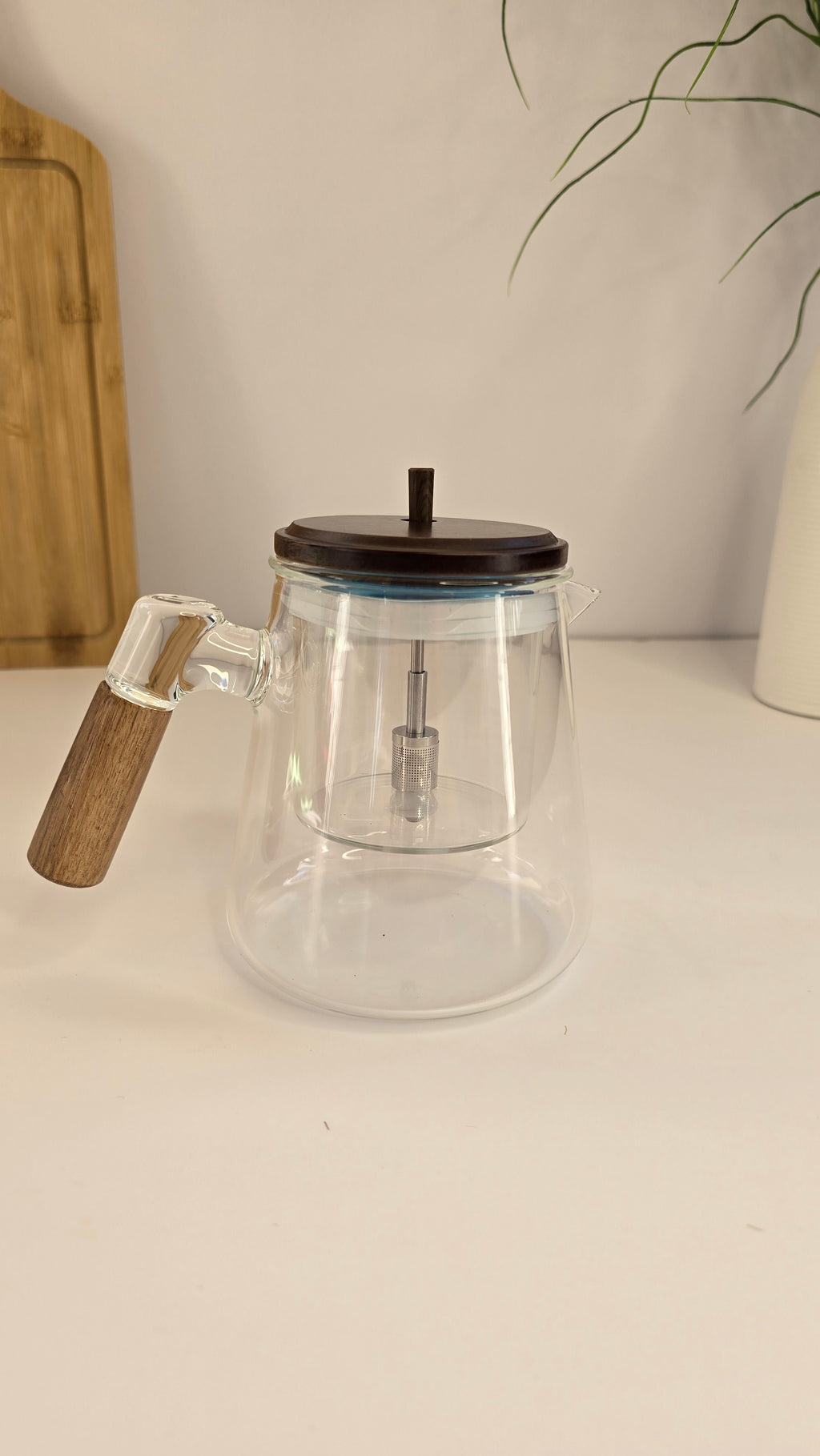 Side view of the clear glass teapot with removable infuser and wooden-look handle