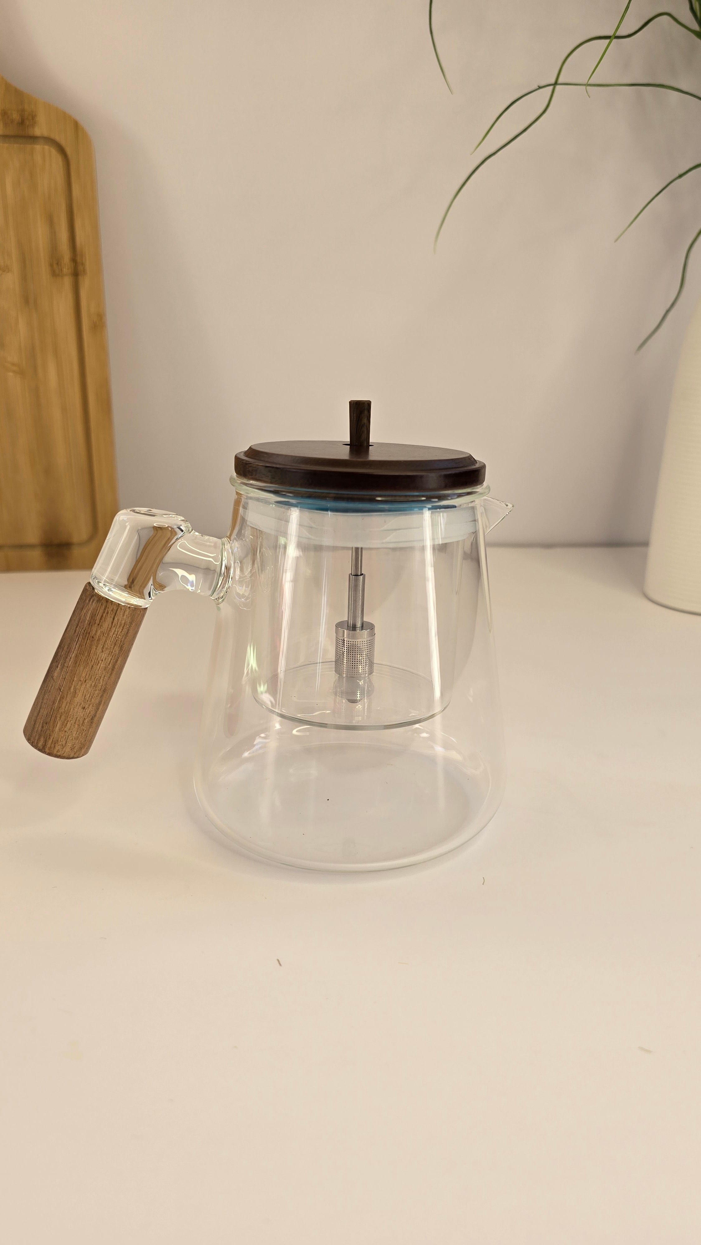 Side view of the clear glass teapot with removable infuser and wooden-look handle