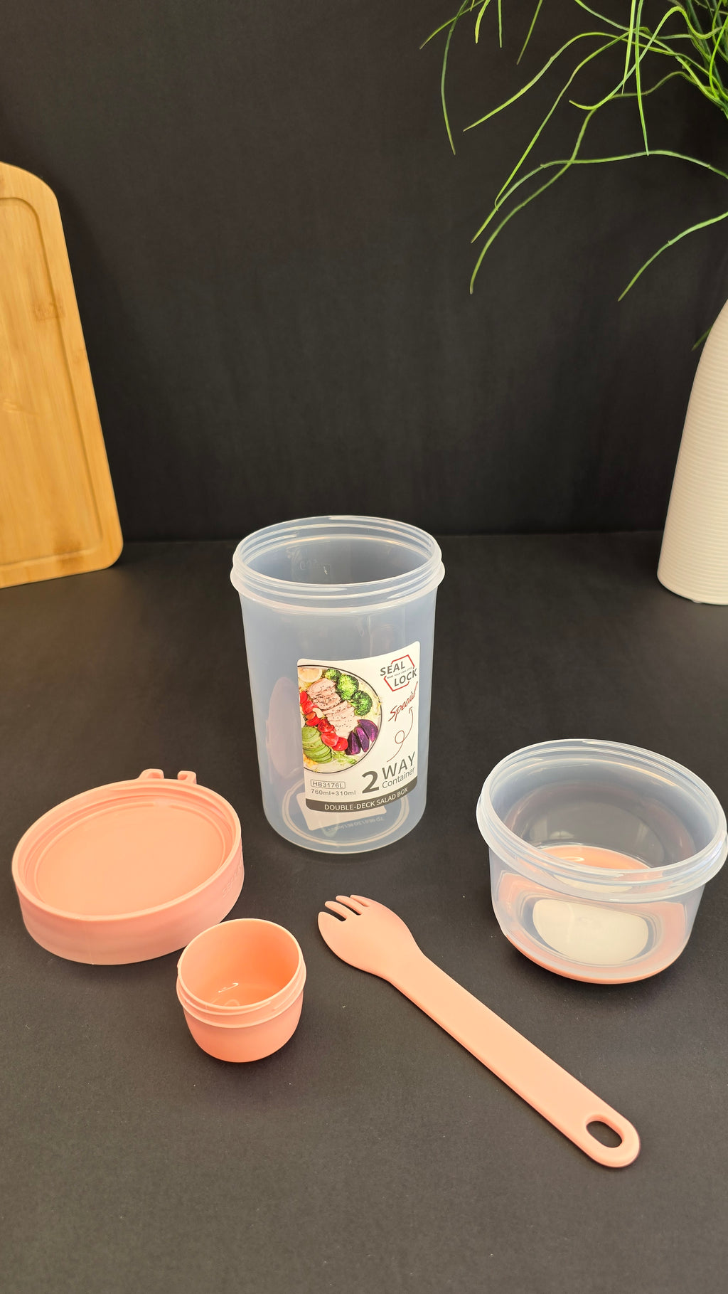 Disassembled two-compartment salad container with dressing cup, lids and reusable fork
