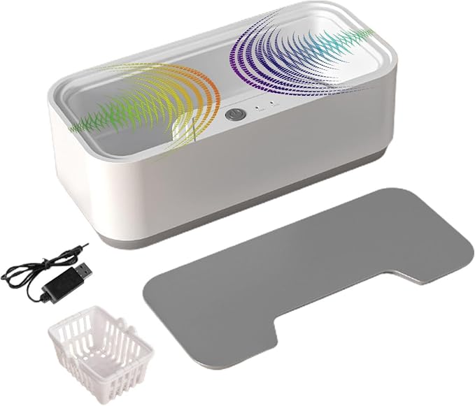A white rectangular ultrasonic cleaner kit shown on a light gray background, including the main cleaner unit with colorful soundwave graphics, a gray lid, a USB charging cable, and a small white basket.