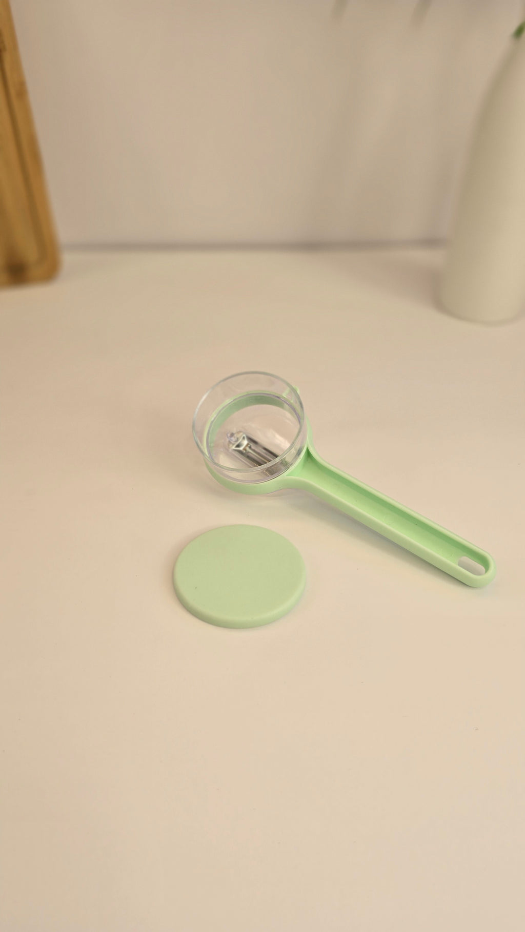 Light green Beiryta vegetable peeler with transparent peel collector shown from the side