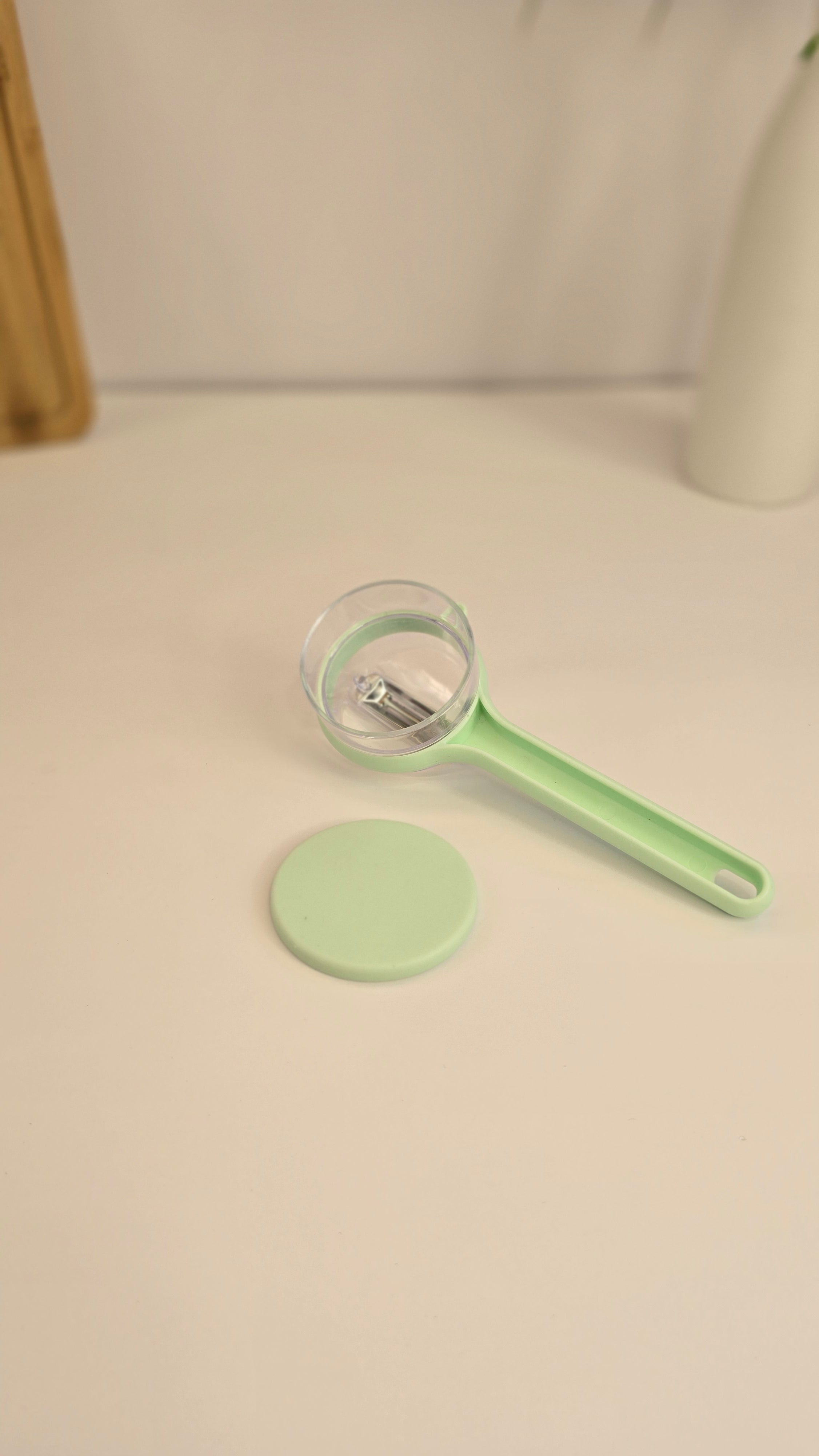 Light green Beiryta vegetable peeler with transparent peel collector shown from the side