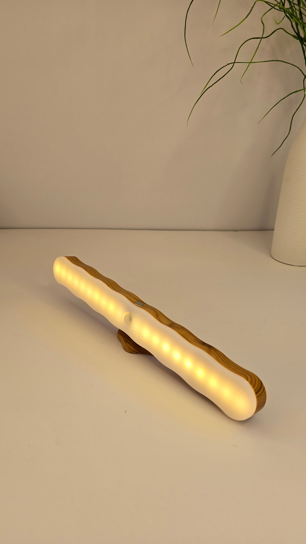 Angled view of the glowing rechargeable LED night light with wavy diffuser and wood-effect trim