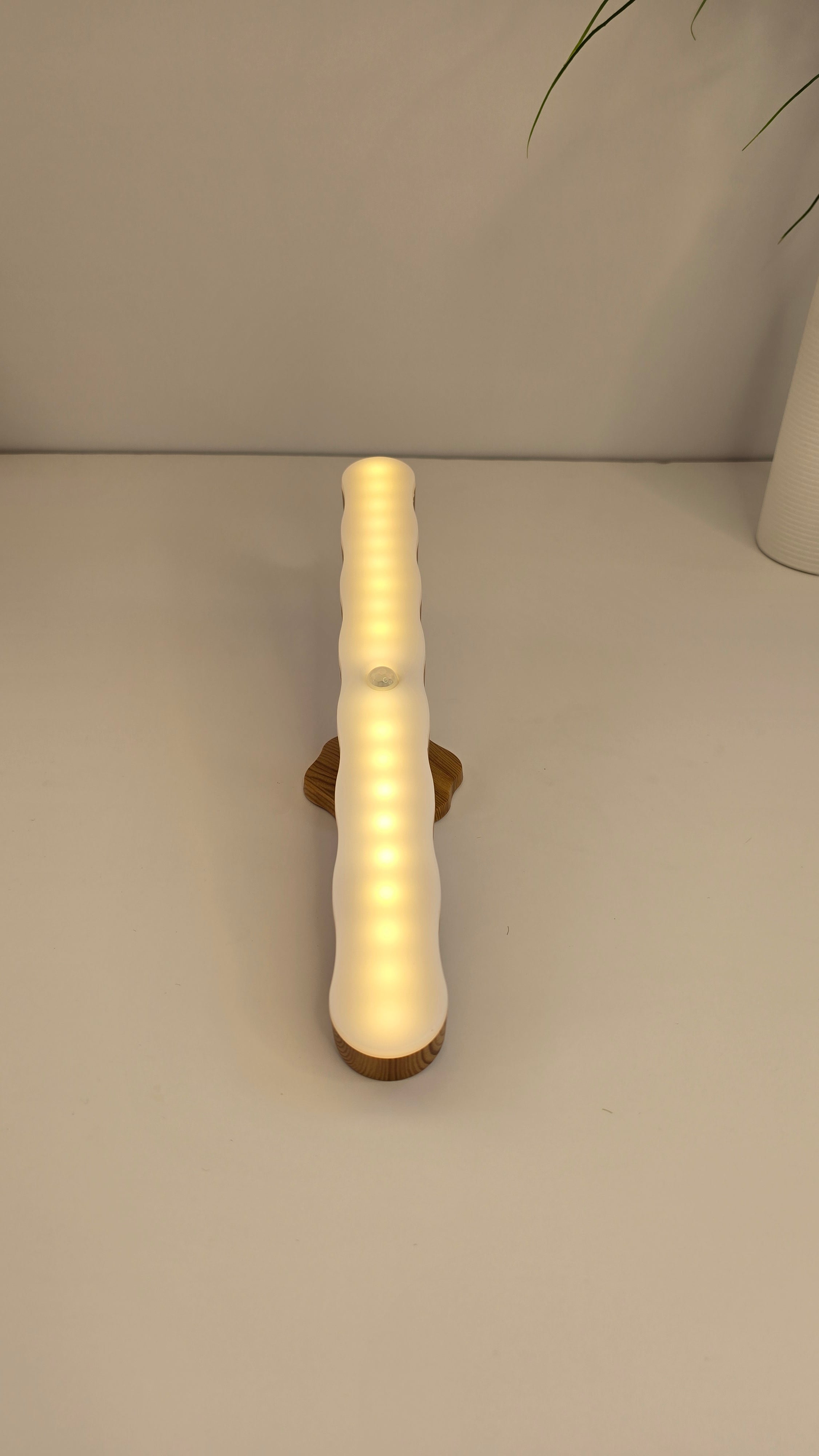 Front view of the Beiryta rechargeable warm LED night light illuminated on its wood-effect stand