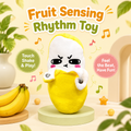 A plush fruit-themed rhythm toy shaped like a yellow banana character with a white face and pink cheeks, standing on a round pedestal. The scene includes large text reading 'Fruit Sensing Rhythm Toy,' callout bubbles about touching and playing, decorative leaves, stars, and bananas in a styled indoor setup.