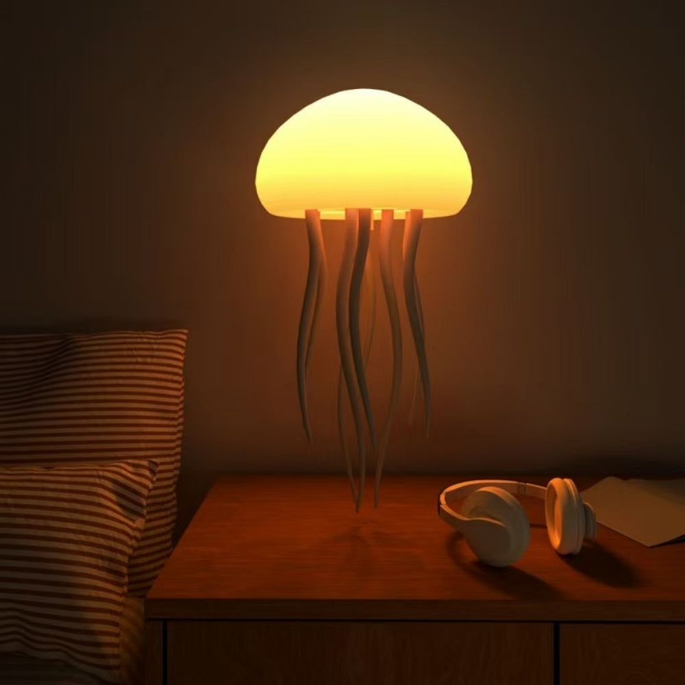 Jellyfish-shaped lamp on a bedside table with headphones and a pillow in a dimly lit room.