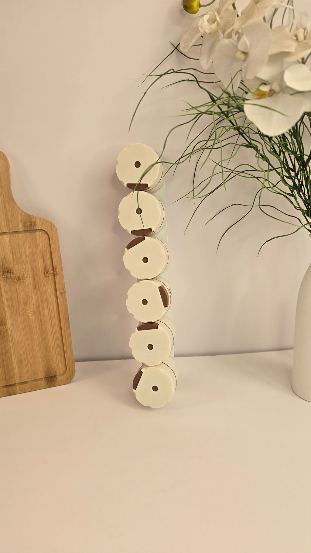 Six cream magnetic spice dispensers displayed vertically on a mounting strip