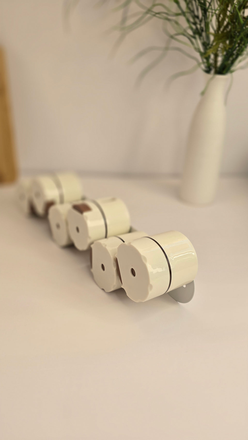 Close-up of six cream magnetic spice dispensers with push-release controls
